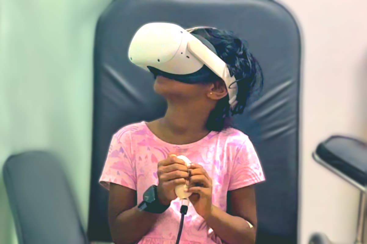 A child wearing the research headset and holding the tactile squeeze input while seated